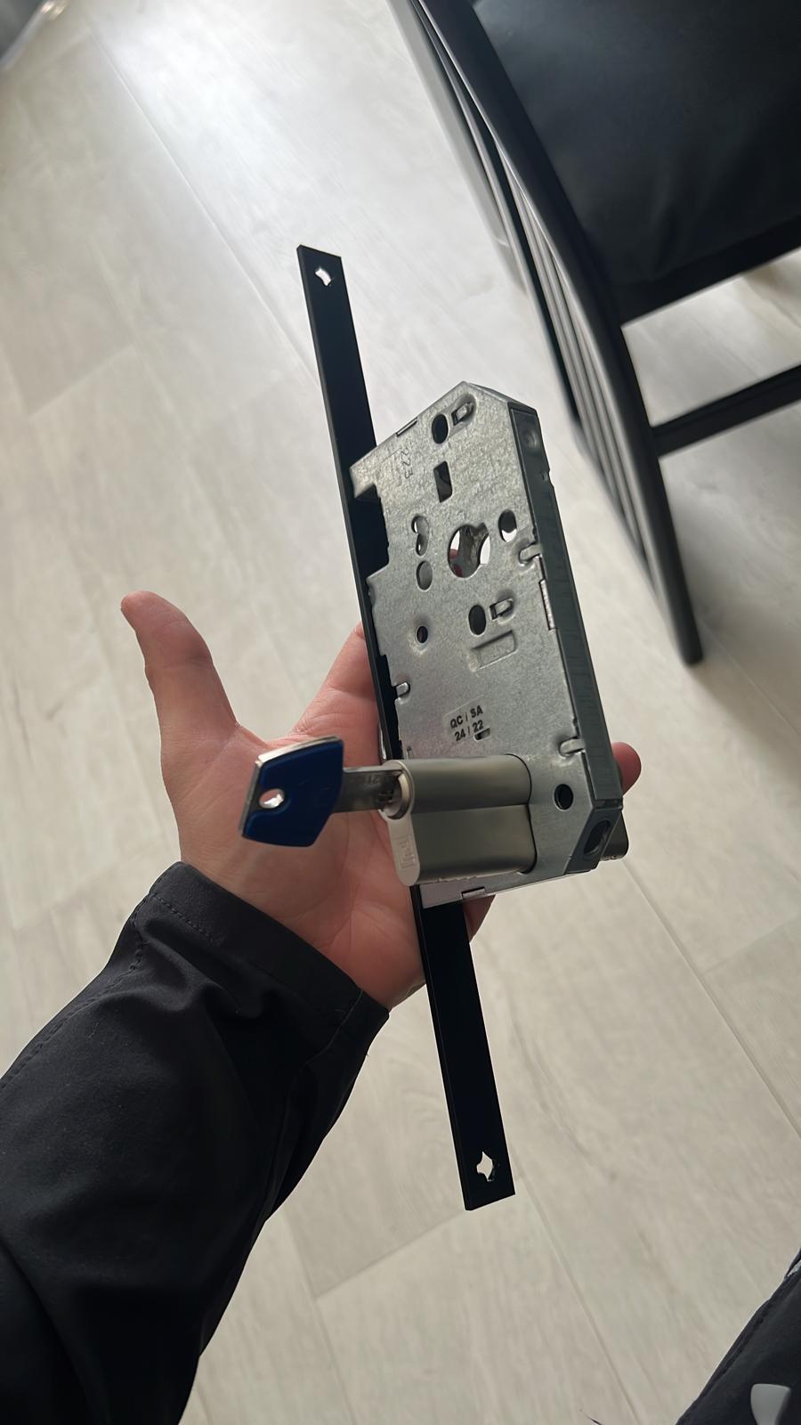 une serrure monopoint avec un cylindre dans une main.